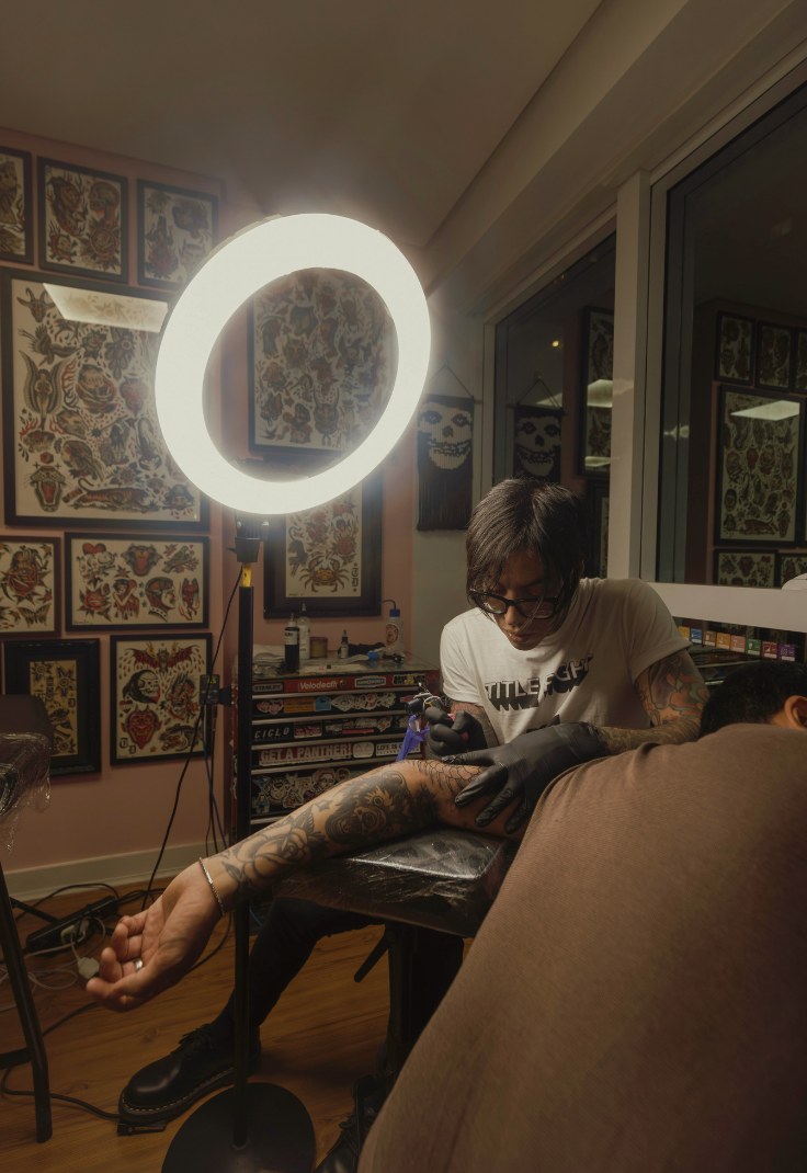Tattoo studio interior with ring light and artist at work